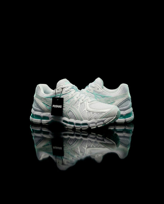 ASICS Gel-Kayano 20 'Illuminate Mint' (2026) white and mint runner on a black reflective surface with a PUSHAS tag
